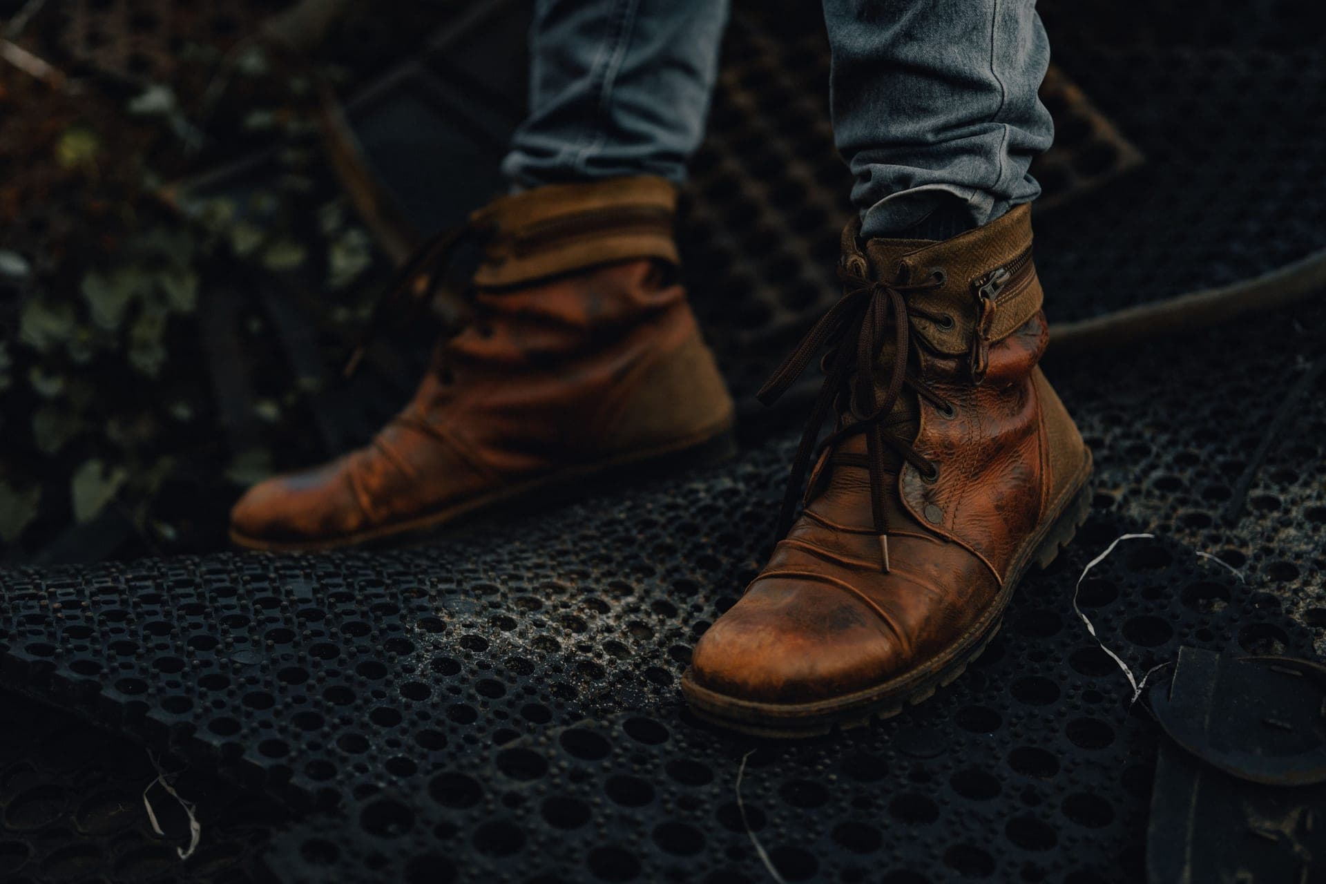 A pair of leather work boots lit from one side against a dark background