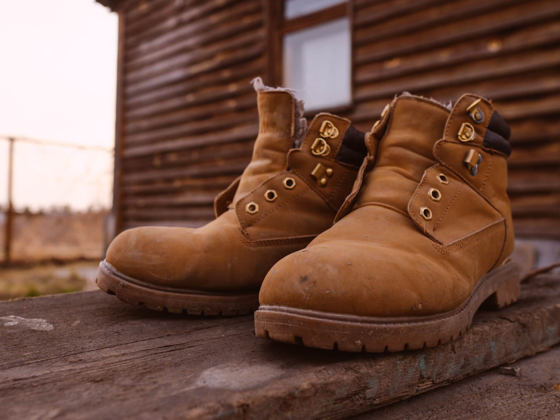 A new leather work boot with unmarked soles beside a worn pair