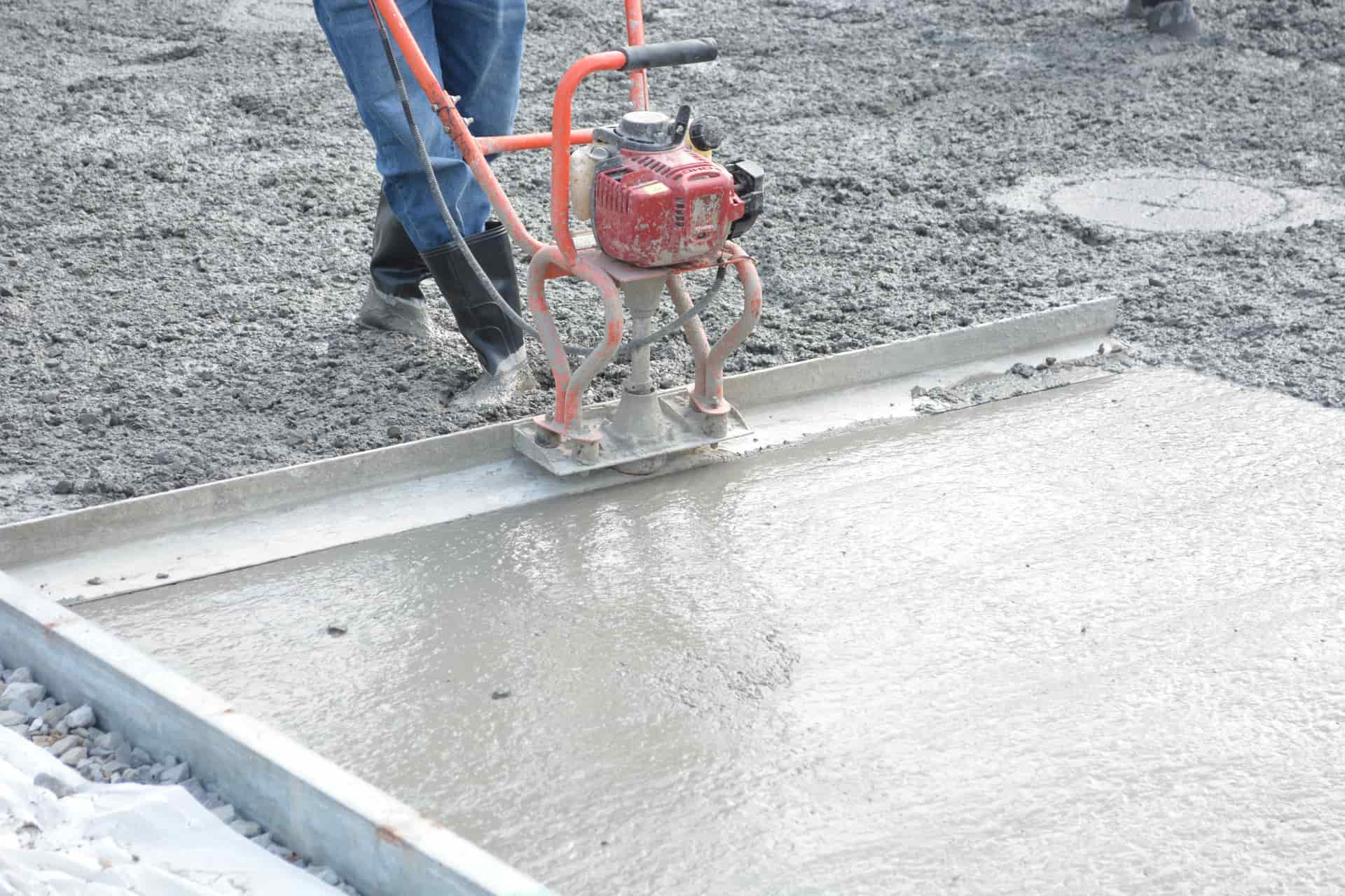 A worker screeding a freshly poured concrete slab