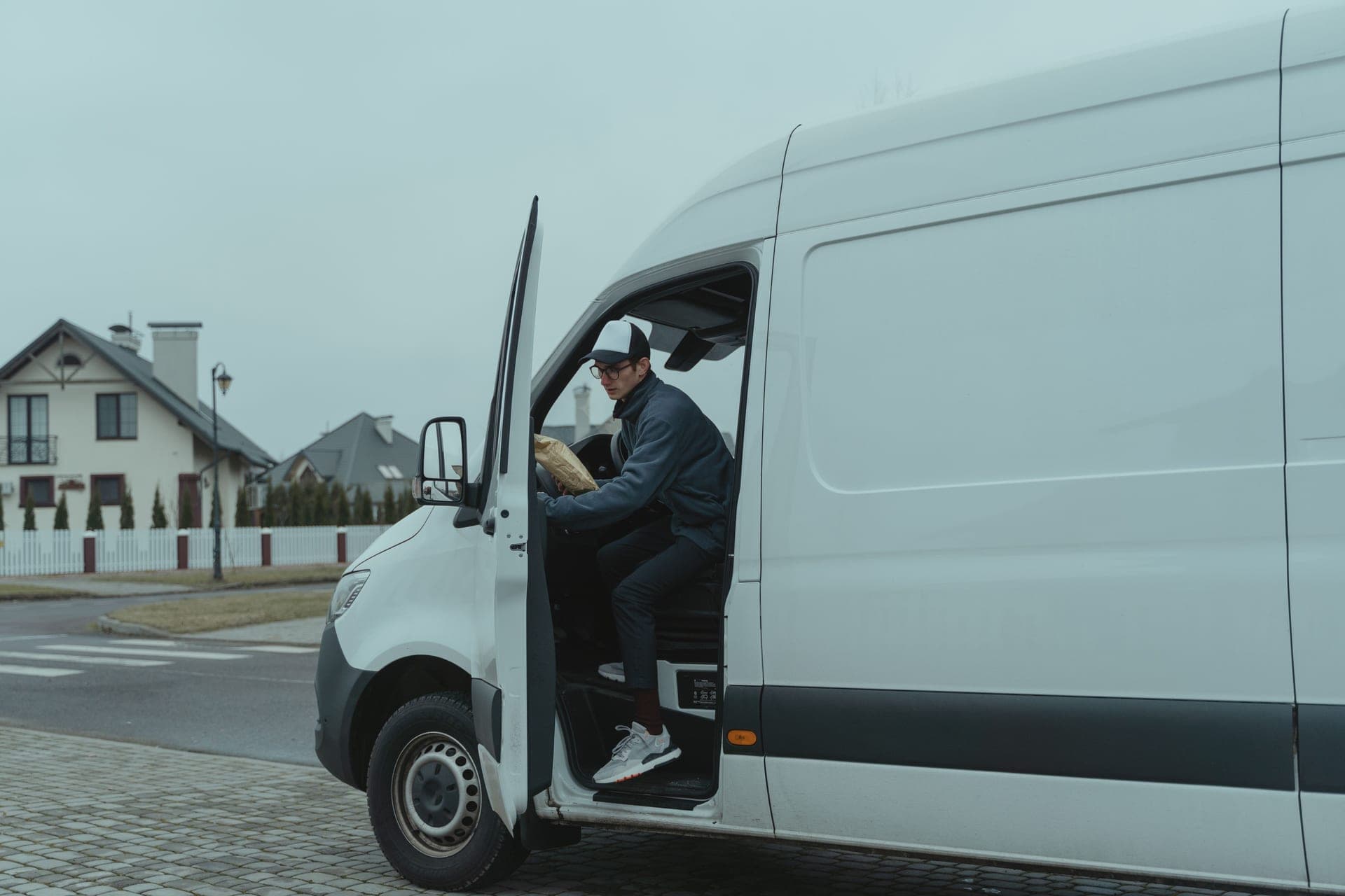 A delivery driver stepping down from a van with a parcel