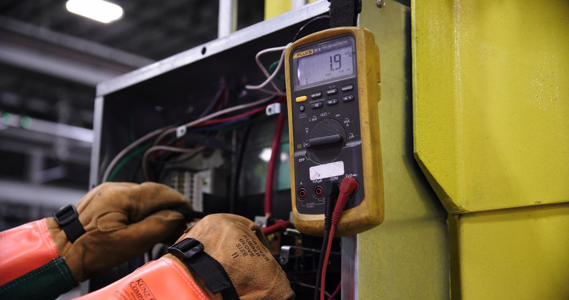 An electrician working at an open electrical panel