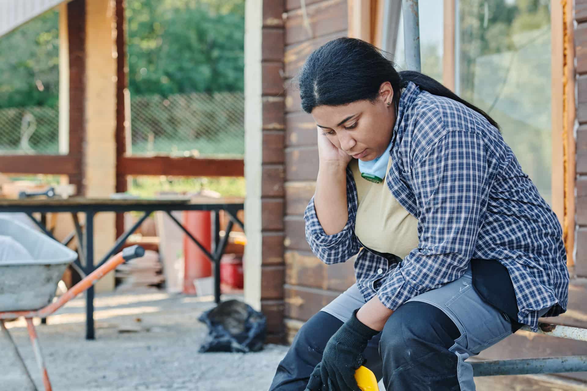A worker sitting on a step with their boots off at the end of a shift