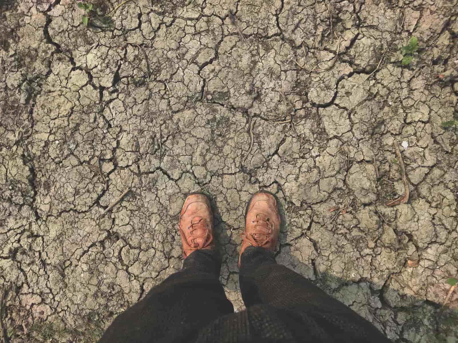 A worker's boots on sun-baked ground in bright summer light