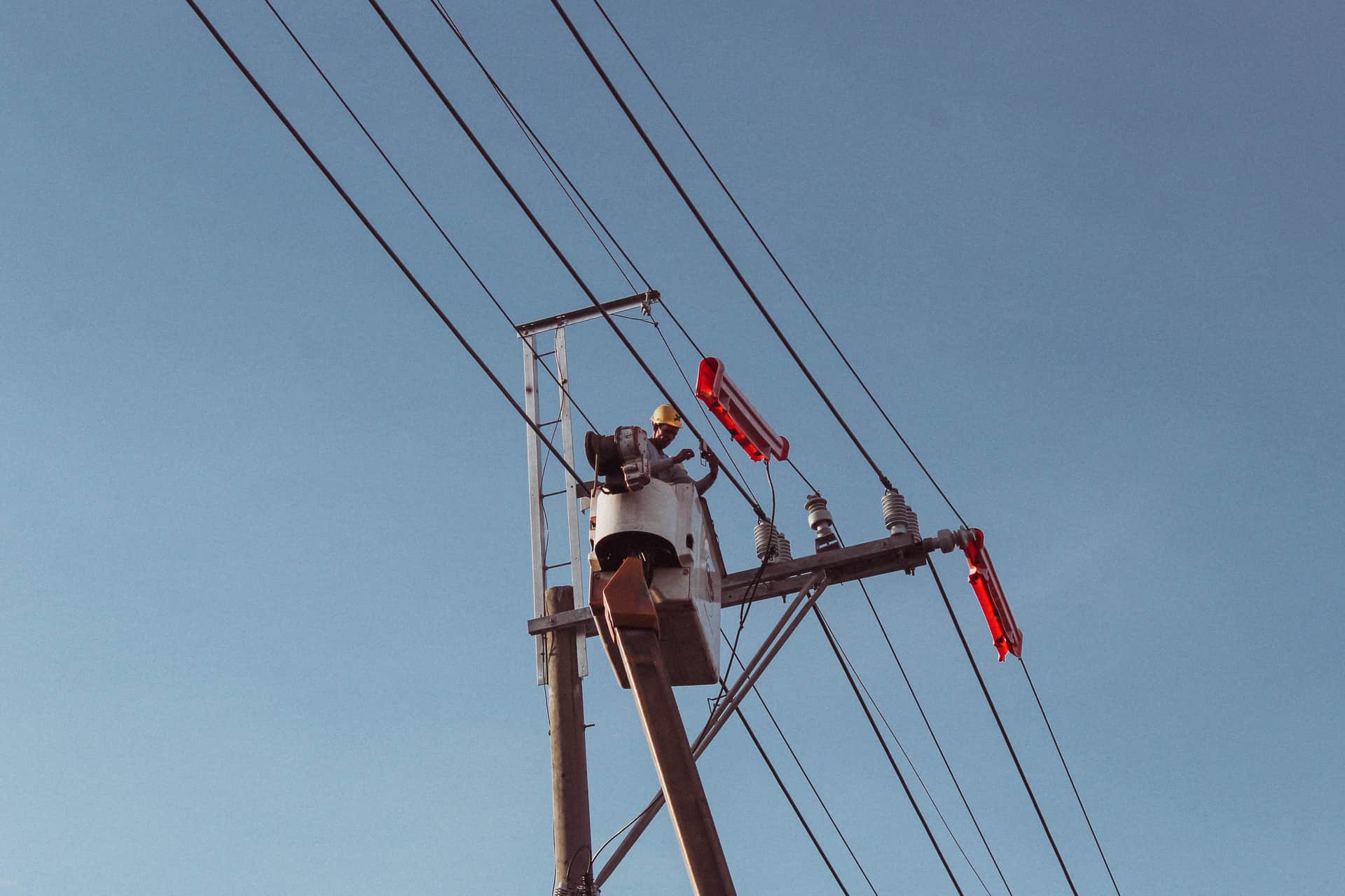 A lineworker on a utility pole against an overcast sky