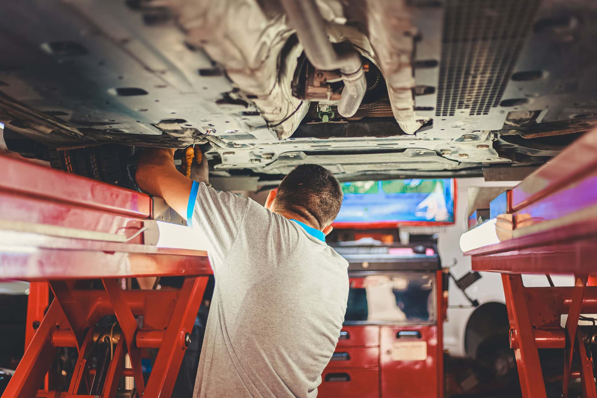A mechanic working under a vehicle on a workshop floor