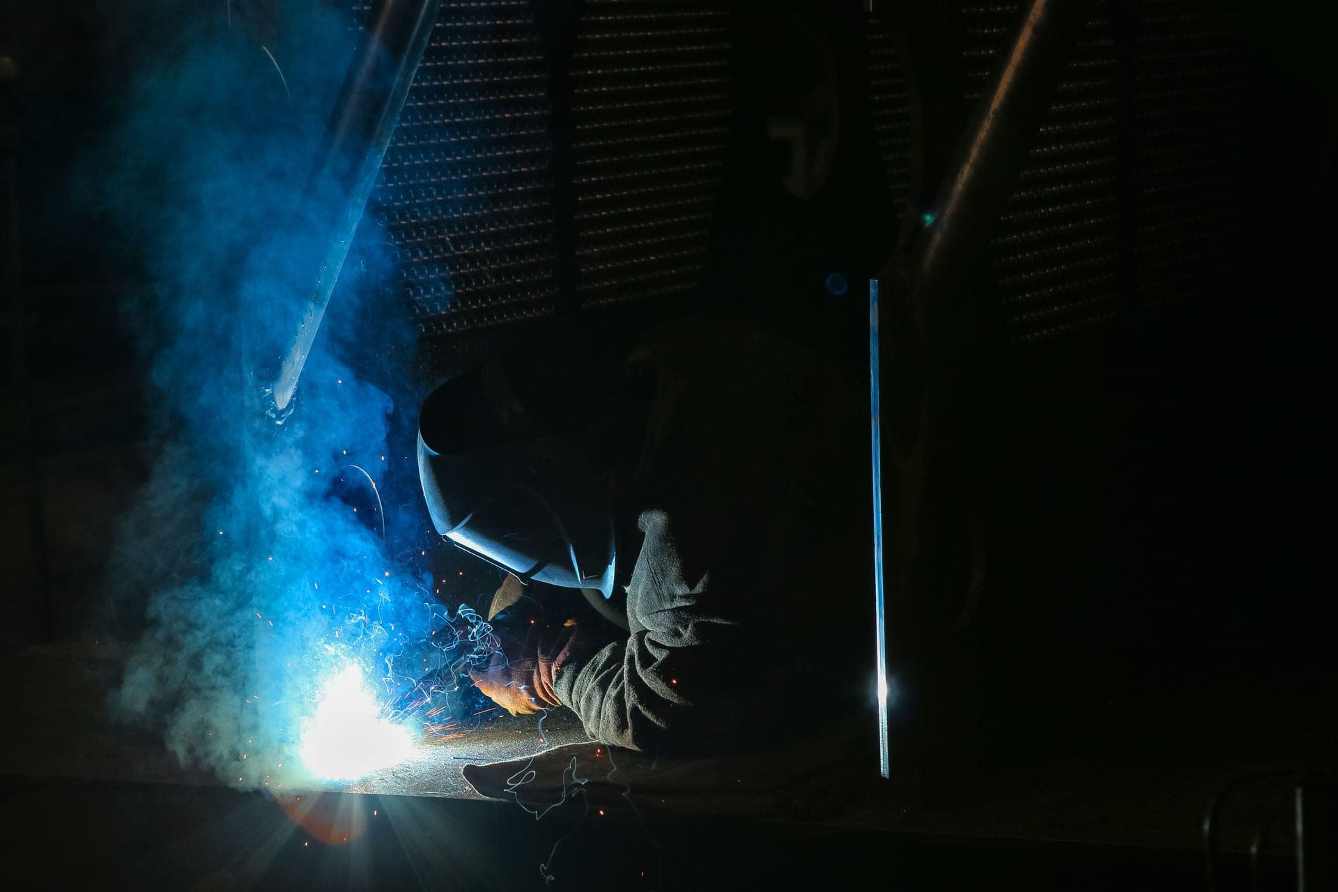 A welder striking an arc, sparks falling toward the floor